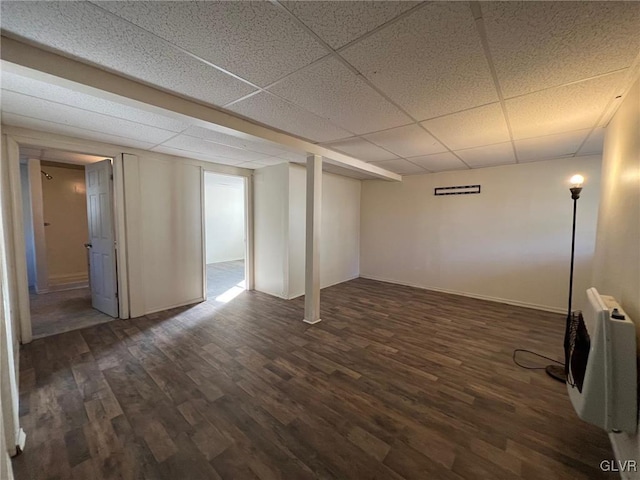 basement featuring heating unit, a drop ceiling, and dark hardwood / wood-style floors