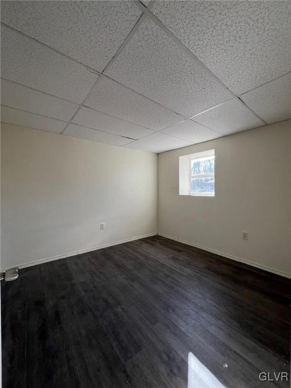 interior space featuring dark wood-type flooring and a drop ceiling