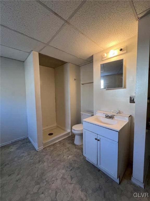 bathroom featuring toilet, vanity, a drop ceiling, and walk in shower