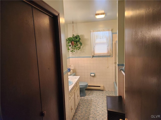 bathroom with toilet, a baseboard heating unit, tile walls, tile patterned floors, and vanity