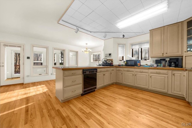 kitchen featuring kitchen peninsula, light hardwood / wood-style flooring, track lighting, black appliances, and an inviting chandelier