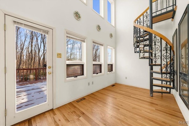 entrance foyer featuring light wood-type flooring, visible vents, stairway, and a towering ceiling