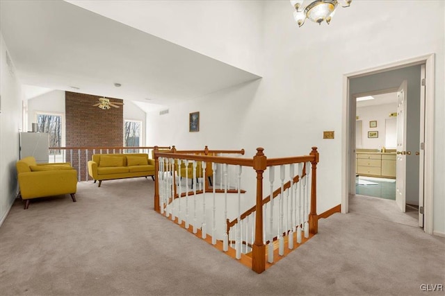 corridor with light carpet, baseboards, lofted ceiling, and an upstairs landing