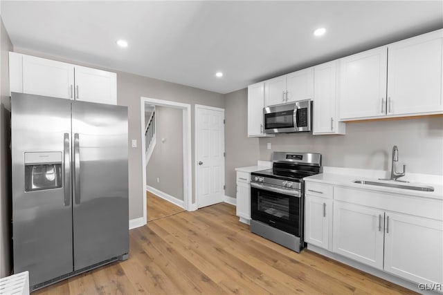 kitchen featuring white cabinets, appliances with stainless steel finishes, sink, and light hardwood / wood-style floors