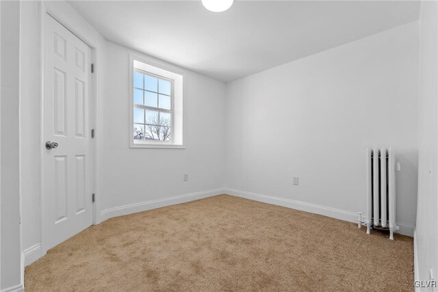 spare room with radiator and light carpet