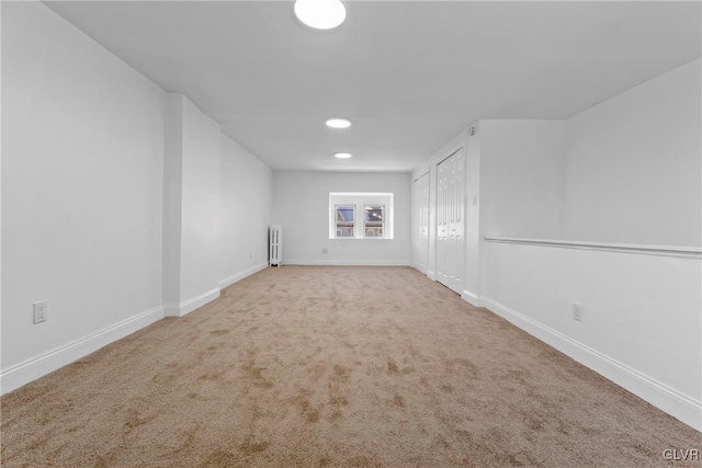 unfurnished room featuring light carpet and radiator