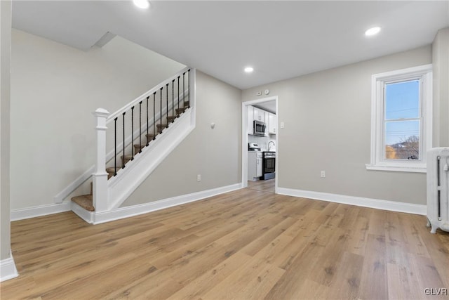 unfurnished living room featuring light wood-type flooring and radiator heating unit