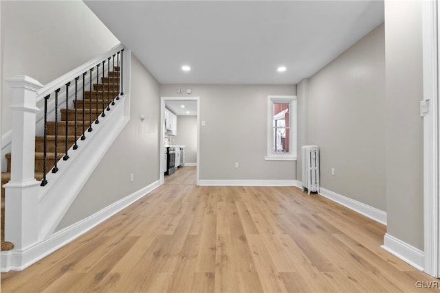 unfurnished living room featuring radiator heating unit and light hardwood / wood-style flooring