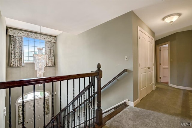 corridor featuring a notable chandelier and dark carpet