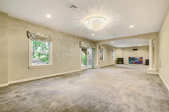 unfurnished living room with light colored carpet, ornate columns, and a healthy amount of sunlight