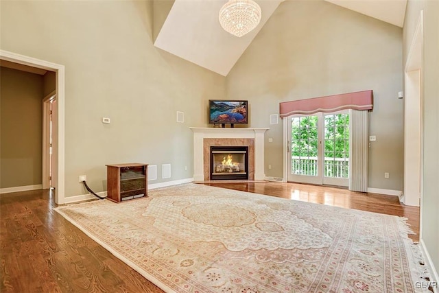 unfurnished living room featuring high vaulted ceiling, a fireplace, and hardwood / wood-style flooring