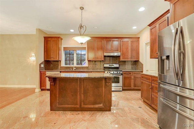 kitchen featuring a center island, stainless steel appliances, sink, hanging light fixtures, and light stone counters