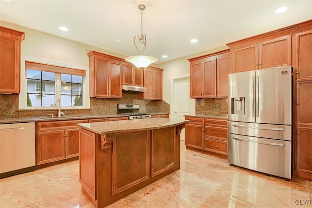 kitchen with stainless steel appliances, a center island, hanging light fixtures, light stone countertops, and sink