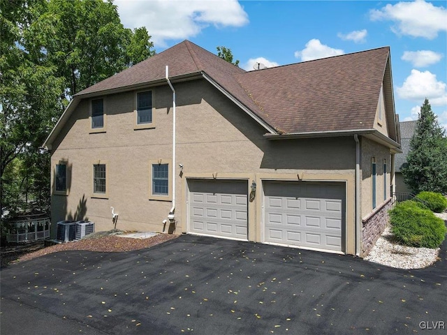 view of side of home with a garage and central air condition unit