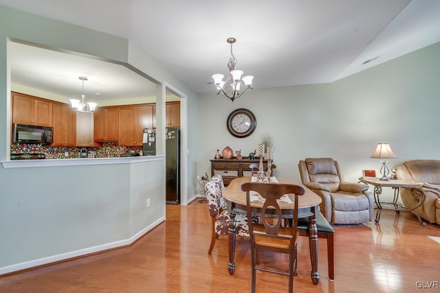 dining room featuring light wood-type flooring and an inviting chandelier