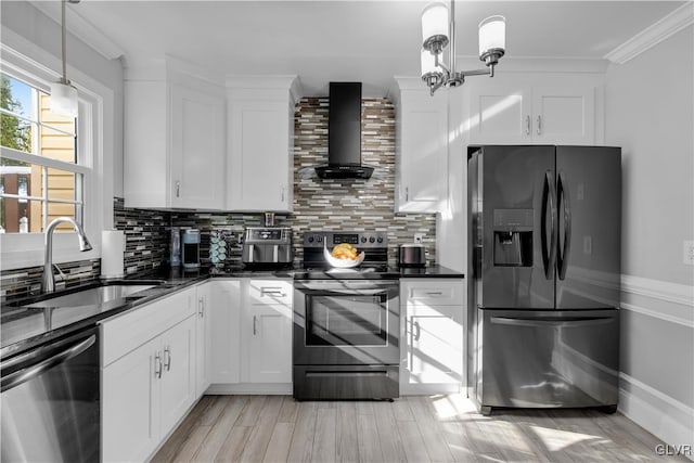 kitchen featuring decorative light fixtures, white cabinetry, wall chimney range hood, stainless steel appliances, and sink