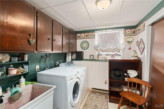 washroom featuring washing machine and clothes dryer, baseboard heating, a sink, and cabinet space