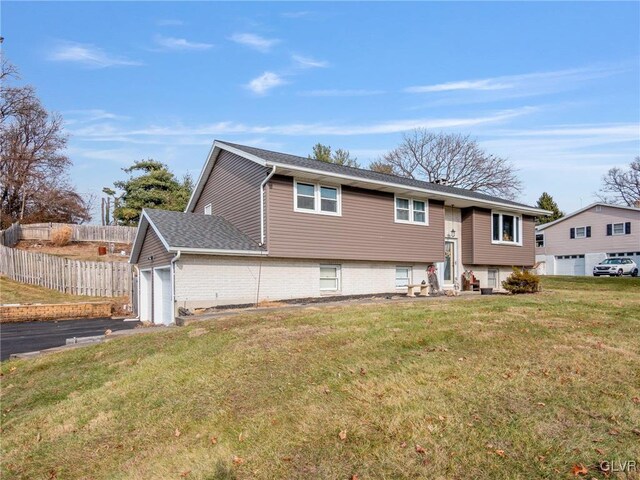 raised ranch featuring a garage and a front lawn