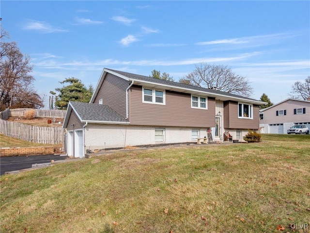 raised ranch featuring a shingled roof, an attached garage, fence, and a front lawn