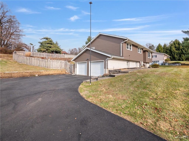 view of side of property featuring a yard, aphalt driveway, fence, and brick siding