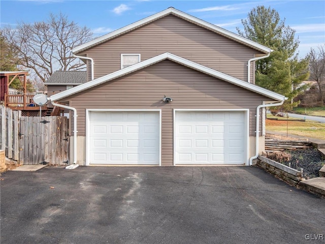 garage featuring driveway and fence