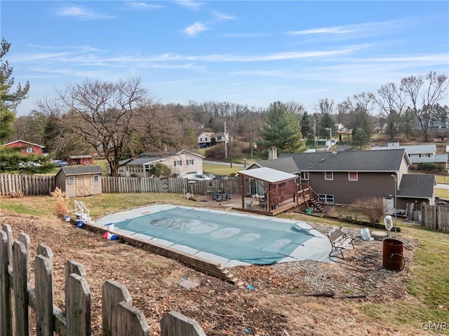 view of swimming pool with a fenced backyard, an outdoor structure, a wooden deck, a fenced in pool, and a storage unit