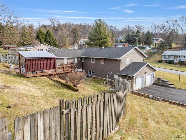 view of front of property with a garage, aphalt driveway, fence, a deck, and a front yard