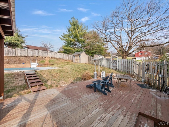 wooden deck featuring a fenced backyard, a storage unit, a lawn, and an outbuilding