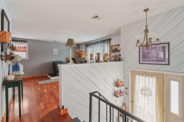 interior space with baseboards, visible vents, wood finished floors, a textured ceiling, and a notable chandelier