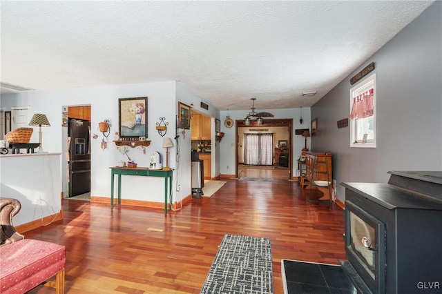 interior space with a textured ceiling, wood finished floors, and a wood stove