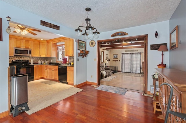 kitchen featuring light wood-type flooring, light brown cabinets, decorative light fixtures, and black appliances