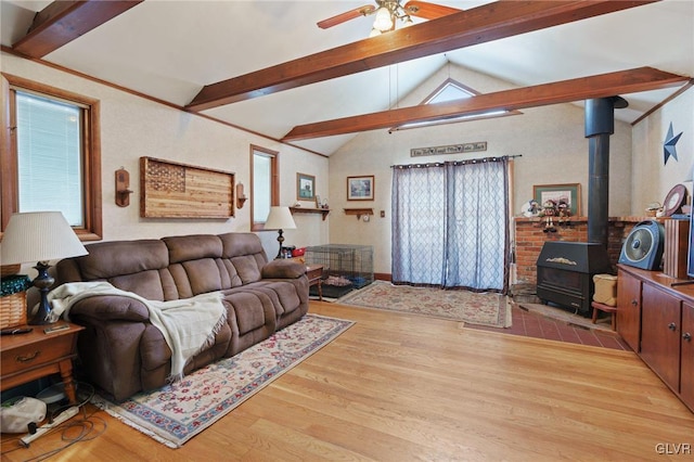 living area with a wood stove, light wood-style flooring, lofted ceiling with beams, and a wealth of natural light