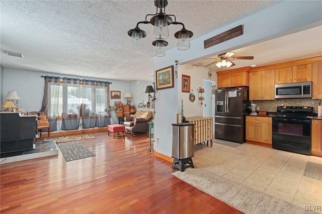 kitchen with tasteful backsplash, visible vents, light wood-style floors, brown cabinets, and black appliances