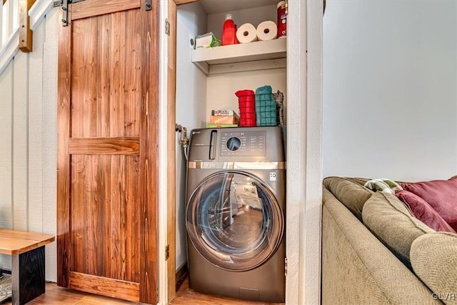 laundry area with washer / clothes dryer, light wood-type flooring, and a barn door