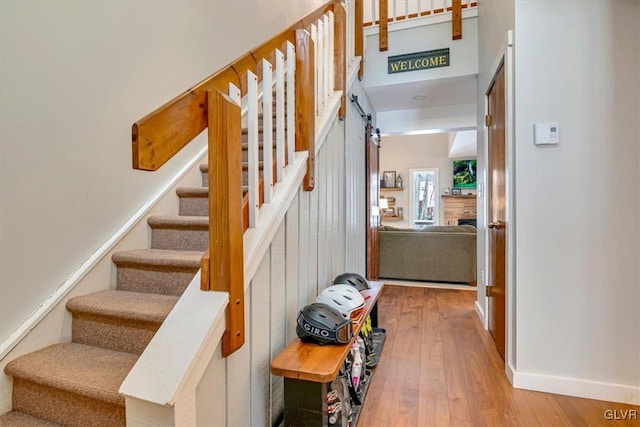 staircase featuring a fireplace, hardwood / wood-style floors, and a barn door