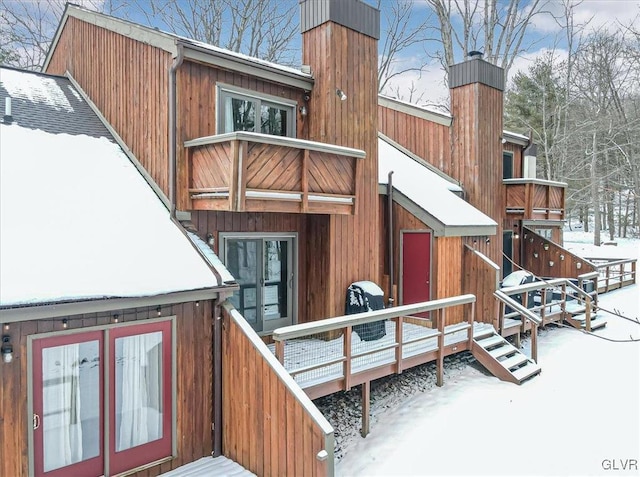 snow covered rear of property with a wooden deck