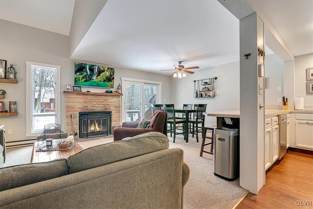 living room with ceiling fan, a baseboard radiator, light wood-type flooring, and a healthy amount of sunlight