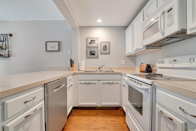 kitchen featuring sink, white appliances, light hardwood / wood-style flooring, and white cabinets