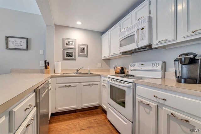 kitchen featuring white cabinets, white appliances, light hardwood / wood-style floors, and sink