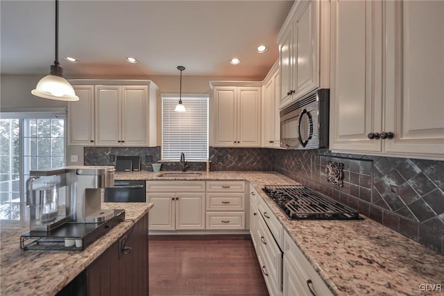 kitchen featuring sink, pendant lighting, white cabinets, and black appliances