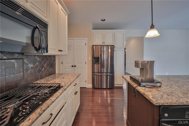 kitchen with hanging light fixtures, light stone countertops, dark hardwood / wood-style floors, black appliances, and decorative backsplash