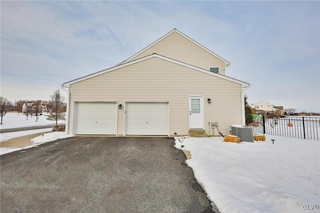 view of snowy exterior featuring a garage and cooling unit