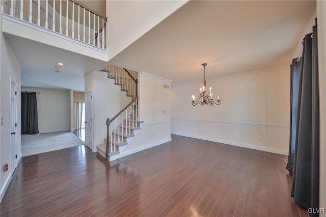 empty room with a notable chandelier and dark hardwood / wood-style flooring