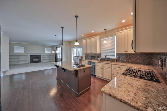 kitchen featuring a kitchen island, light stone counters, stainless steel dishwasher, and a kitchen breakfast bar