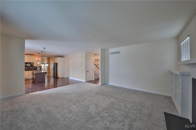 unfurnished living room with a notable chandelier and dark colored carpet