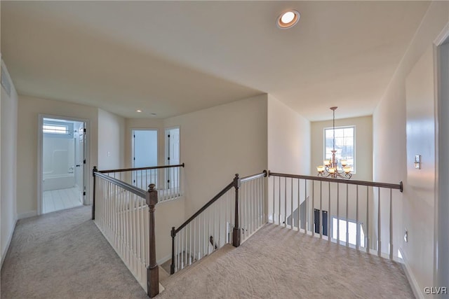 hall with light colored carpet and a notable chandelier