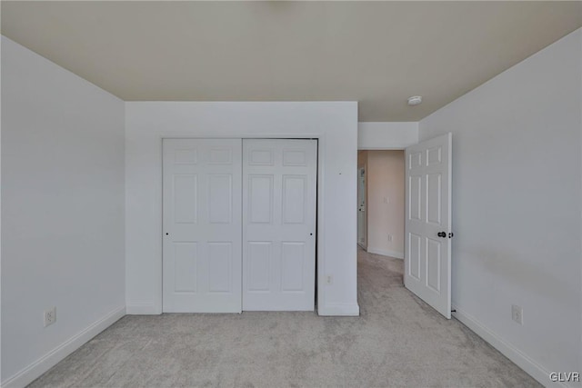 unfurnished bedroom with a closet and light colored carpet