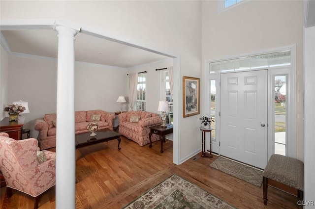 entryway featuring ornamental molding, hardwood / wood-style flooring, and ornate columns