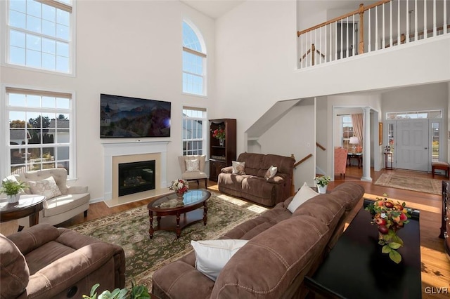 living room featuring a high ceiling, hardwood / wood-style floors, and ornate columns