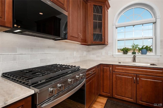 kitchen featuring sink, light hardwood / wood-style flooring, tasteful backsplash, and stainless steel range with gas stovetop